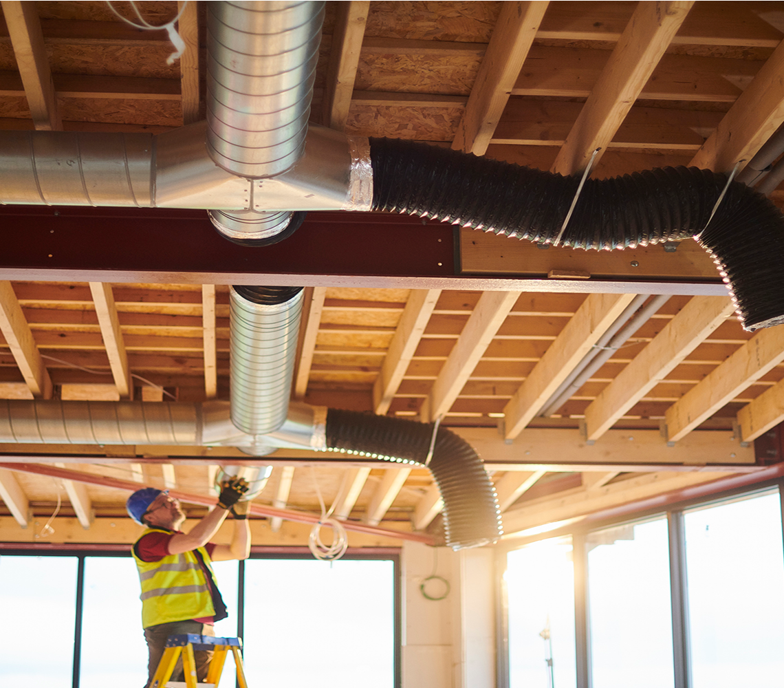 Worker installing HVAC ducts in building