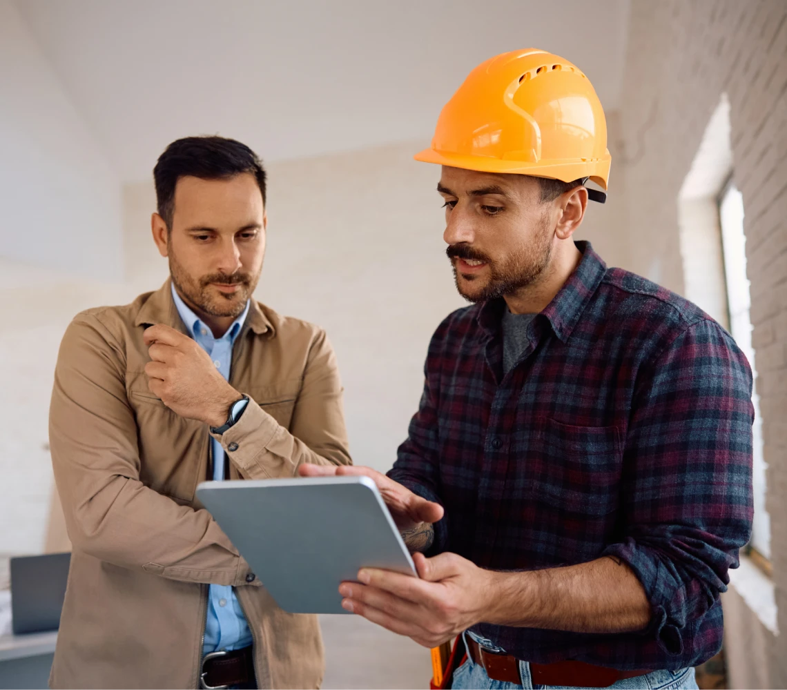Builder and colleague reviewing digital plans